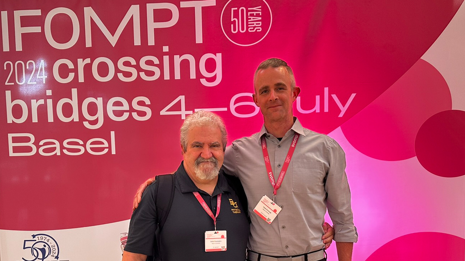 Louie Puentedura and Casey Unverzagt pose in front of the IFOMPT Conference sign. 