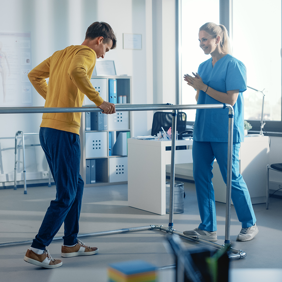 Physical therapist assisting patient using parallel bars for walking.