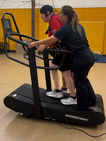 A man walks on a treadmill while wearing gear to record vitals. 