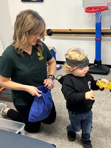 A woman assists a young child during a physical therapy session. 