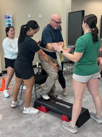 Doctor of Physical Therapy (DPT) students assist a man who is participating in a step-up exercise activity. 